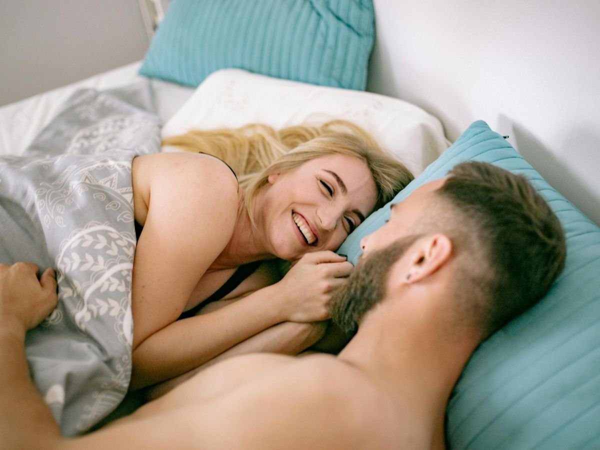 Happy couple sharing a light moment in bed, representing intimacy and trust with the best brand of condoms to buy for safe pleasure.